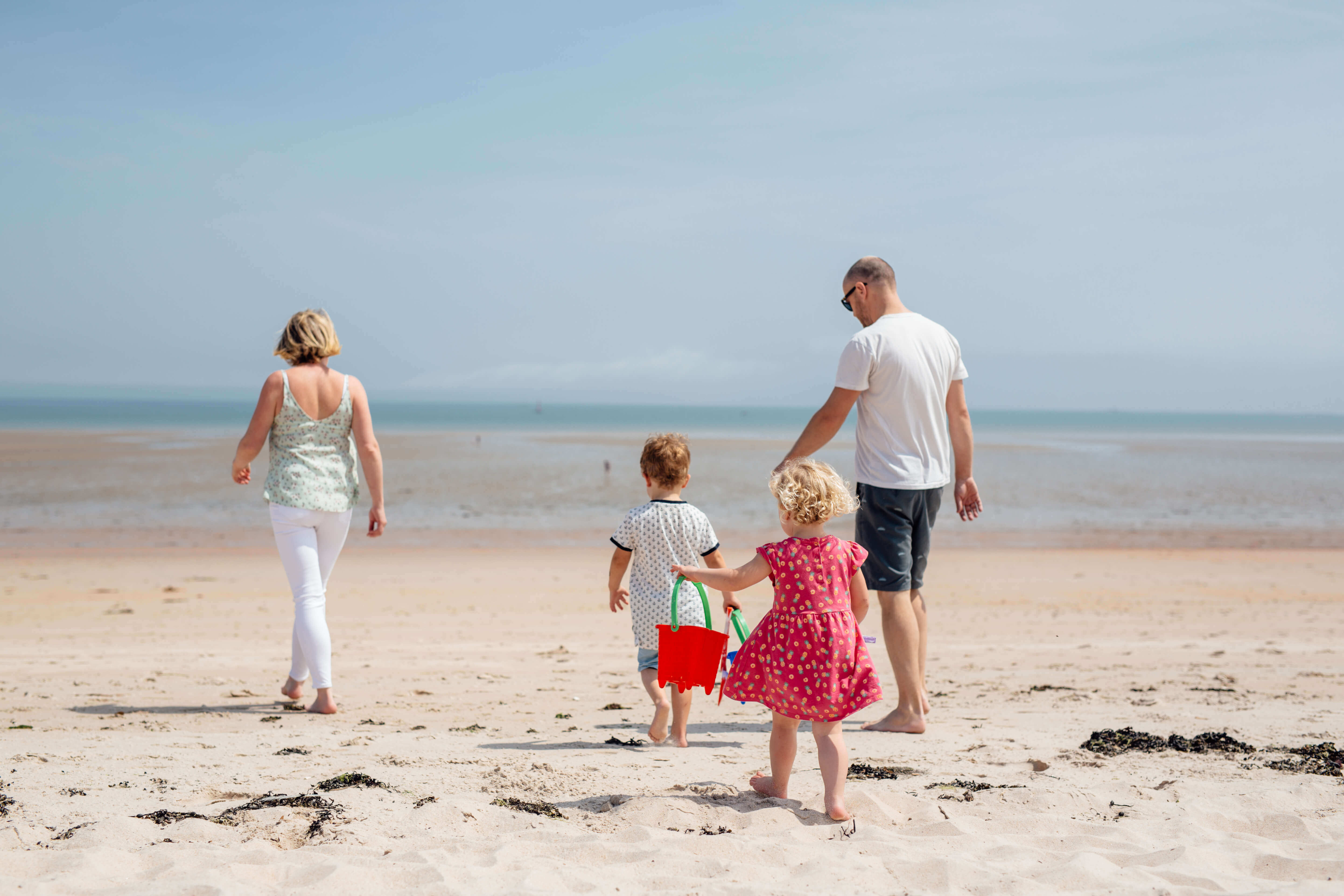 a family walking along the golden sands on a beach in jersey