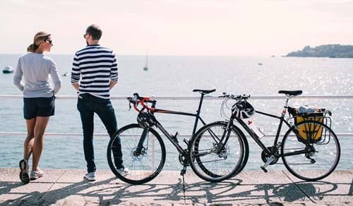 couple with their bicycles looking over sea in jersey channel islands