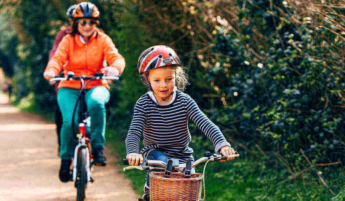 little girl cycling with family behind on cycle path